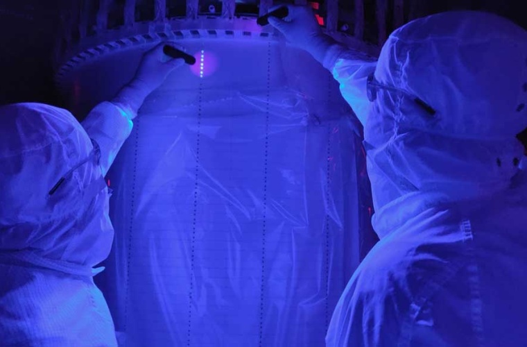 SURF-Techniker Derek Lucero (l.) und Forscher Tomasz Biesiadzinski suchen mit UV-Licht nach möglicher Staubkontamination in der Zeitprojektionskammer des Detektors.