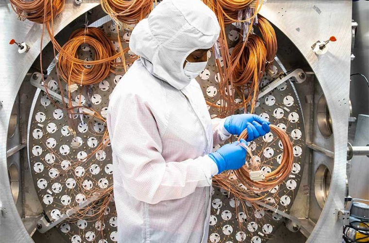 Die Forscherin Alvine Kamaha schneidet die Kabel für die Photomultiplier-Röhrenanordnung im Detektor.