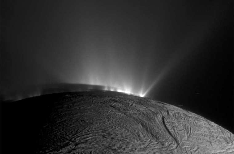 Blick über den Südpol des eisigen Saturnmondes Enceladus: Aus Rissen in der eisigen Oberfläche des Mondes, die als „Tigerstreifen” bekannt sind, spritzt Material heraus. Enceladus Schatten ist deutlich auf den unteren Teilen der Fontänen zu sehen.