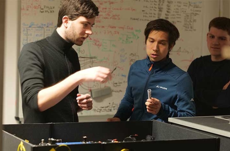 Tobias Bauer (links) und Marlon Schäfer (rechts) von der Universität des Saarlandes und Tim Strobel von der Universität Stuttgart (Mitte) bei der Vorbereitung eines Experimentes mit mobilen Quantenfrequenzkonvertern.