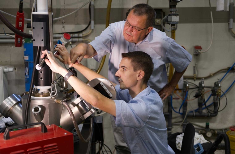 Materialforscher Ralf Busch (stehend) und sein Doktorand Lucas Eisenhut an der Apparatur, in der die Elemente der metallischen Gläser zusammengeschmolzen und homogenisiert werden. Auch die Legierungen für die Versuche auf der ISS wurden hier hergestellt.
Quelle: Claudia Ehrlich, Universität des Saarlandes