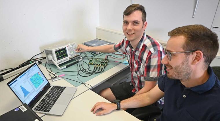 Zwei wissenschaftliche Mitarbeiter wenden die vollintegrierte Ising-Maschine...
