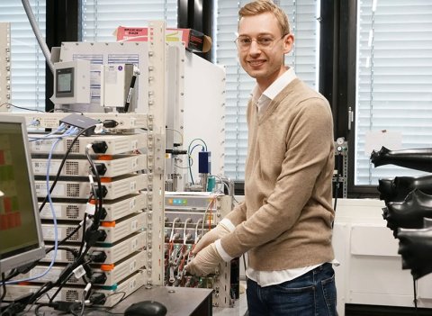 Fabian Apfelbeck arbeitet an einem Messgerät, mit dem sich Lade- und Entladezyklen von Knopfzellen untersuchen lassen.