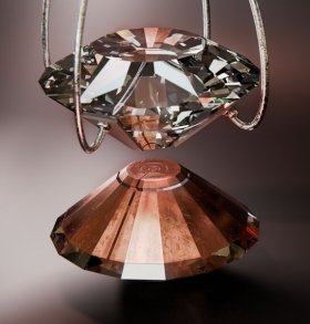 Künstlerische Darstellung der inneren Diamantstempelzelle. Auf dem unteren Diamantstempel befindet sich eine kupferfarbene, mehrstufige Lenzlinse, während am oberen Diamantstempel elektrische Kontakte zur Widerstandsmessung angebracht sind. Im Experiment wird die Materialprobe des Superhydrids im nur wenige hundertstel Millimeter großen Loch in der Mitte platziert.